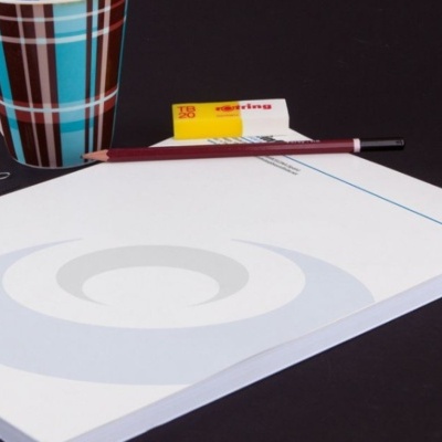 Bloco de notas, lápis, borracha, caneca e clips sobre fundo preto