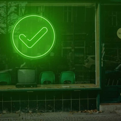Vitrine de loja com luz de néon verde em forma de visto e cartazes