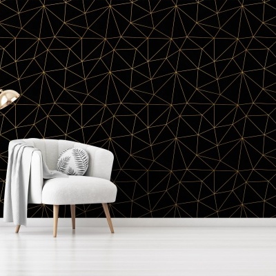 Cadeira cinza com almofada e candeeiro dourado diante de parede preta com padrão dourado