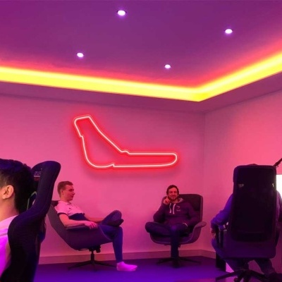 Sala moderna com iluminação roxa e amarela e pessoas em cadeiras com computadores