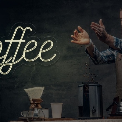 Homem a preparar café com equipamento de filtro em mesa de madeira, fundo escuro e texto 'Coffee'