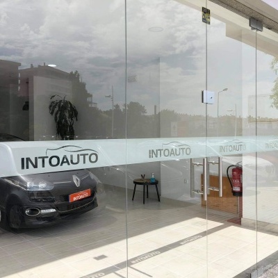 Loja com carro preto em exposição e vidro com faixa adesiva INTOAUTO