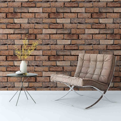 Cadeira bege estofada com mesa de vidro e vaso com flores amarelas em parede de tijolos