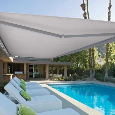 Toldos cinzentos, espreguiçadeiras brancas com almofadas verdes junto a piscina azul exterior