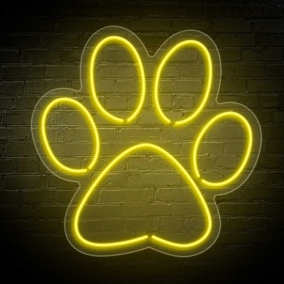 Luz de néon amarela em forma de pata de animal numa parede de tijolo escuro
