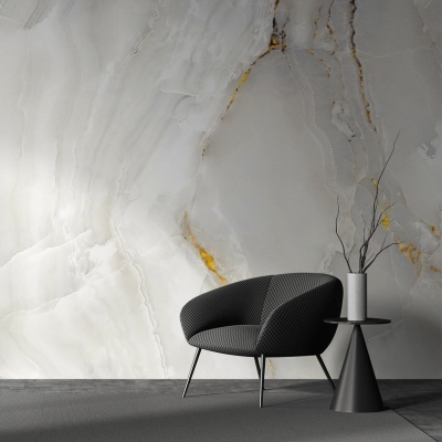 Poltrona escura e mesa lateral preta com vaso em frente a parede de mármore cinza com veios dourados