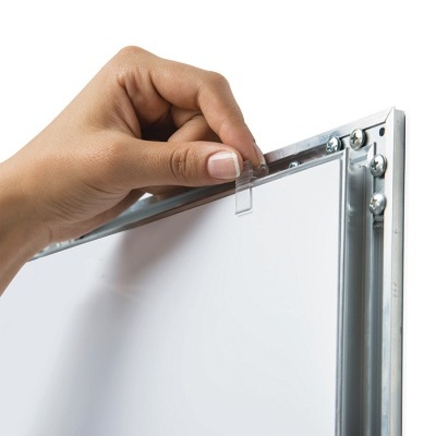 Mão a segurar etiqueta plástica numa moldura metálica de quadro branco