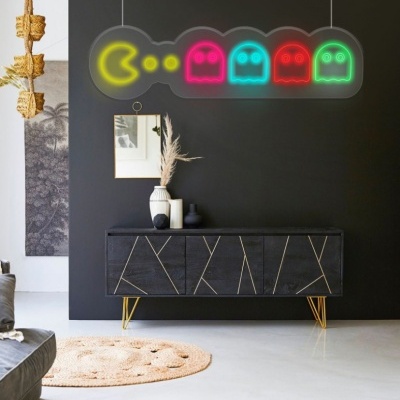 Sala com parede preta, armário escuro, luminária de neon Pac-Man e fantasmas coloridos, e decoração neutra