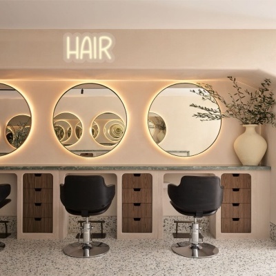 Salão de cabeleireiro com cadeiras pretas e espelhos redondos iluminados