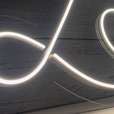 Luz de néon branca em forma de laço e coração sobre madeira escura