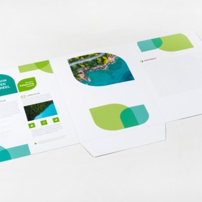 Folhetos abertos com gráficos verdes e azuis e texto em francês sobre superfície branca