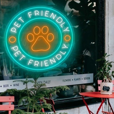 Esplanada com mesas e cadeiras vermelhas e letreiro néon Pet Friendly na janela