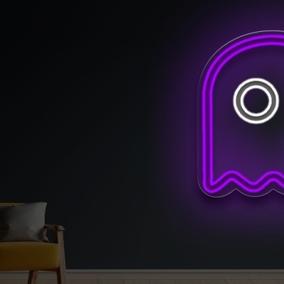 Neon wall art do Pac-Man fantasma roxo com olhos brancos na parede escura ao lado de poltrona amarela