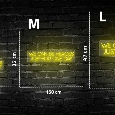Três painéis iluminados a amarelo com texto em inglês e indicação de tamanhos diferentes contra parede de tijolos preta.