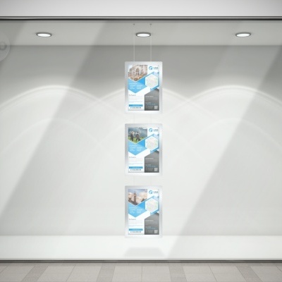 Montra com três cartazes alinhados e iluminados, parede branca e piso azulejado cinzento