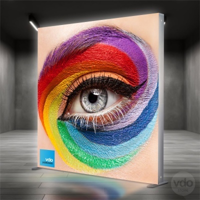 Painel retroiluminado com imagem de um olho pintado com várias cores numa parede interior escura