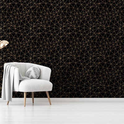 Interior com papel de parede preto geométrico dourado, cadeira branca com almofada e candeeiro dourado