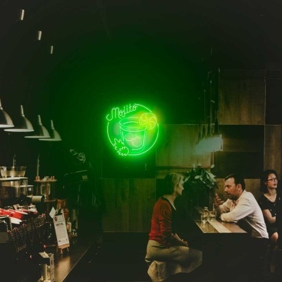 Interior de café escuro com iluminação suave e placa de néon verde