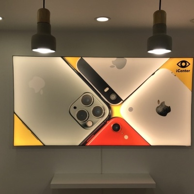 Painel publicitário de iPhones com logo Apple e texto iCenter, numa parede branca