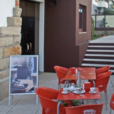 Mesa e cadeiras vermelhas de plástico com utensílios para café, ao ar livre, perto de parede e escadaria