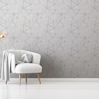 Poltrona branca com almofada e candeeiro de pé dourado junto a parede cinzenta com padrão geométrico