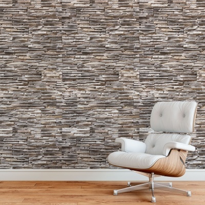 Cadeira branca estofada com estrutura de madeira clara e parede revestida imitação pedra cinza e bege