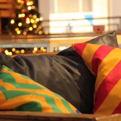 Duas almofadas listradas coloridas e uma almofada preta em ambiente interno com decoração de Natal