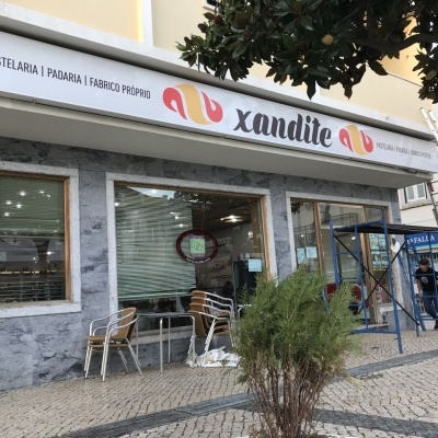 Fachada de pastelaria com sinalização 'xandite' e mesas externas