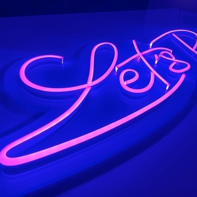 Letreiro de néon rosa com texto LET'S PARTY em fundo azul