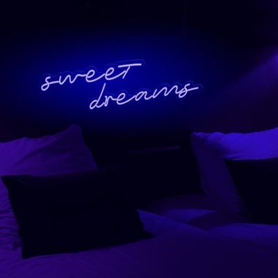 Quarto com cama dupla, almofadas e luz de néon a dizer 'sweet dreams'