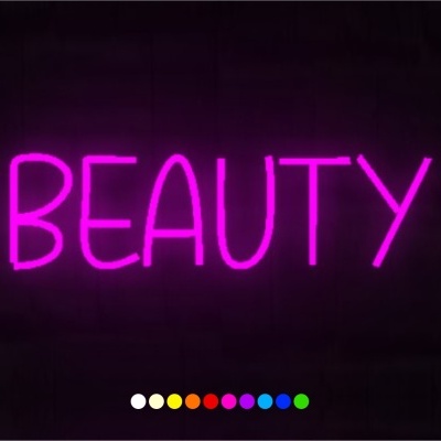 Letreiro em néon rosa com a palavra BEAUTY numa parede preta