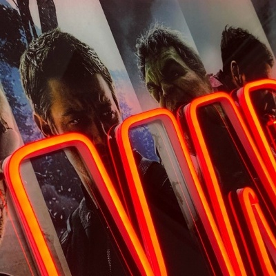 Cartaz de filme com personagens e letreiro de néon vermelho