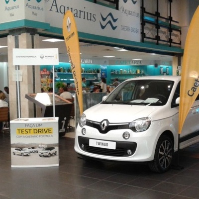 Renault Twingo branco em salão com banners amarelos Caetano Fórmula e expositor TEST DRIVE