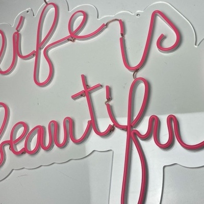 Letreiro LED rosa com as palavras life is beautiful sobre fundo branco