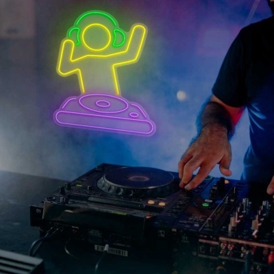 DJ a operar mesa de mistura preta com luzes neon ao fundo