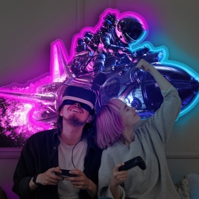 Painel LED de astronauta em neon rosa e azul na parede de sala com duas pessoas a jogar videojogos