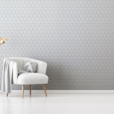 Poltrona branca acolchoada com almofada e candeeiro dourado em parede cinzenta texturizada