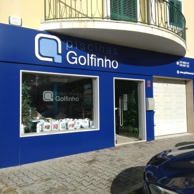 Fachada azul de loja 'piscinas Golfinho' com vitrina e balcão num edifício urbano
