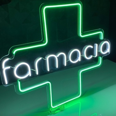 Sinal de neon com cruz verde e texto 'farmacia' em branco