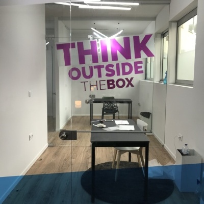 Escritório moderno com porta de vidro decorada com texto THINK OUTSIDE THE BOX