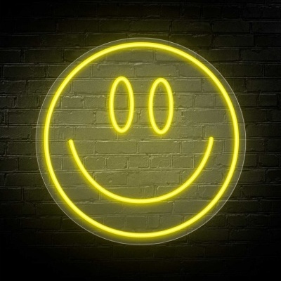 Símbolo de sorriso em neon amarelo numa parede de tijolos escuros