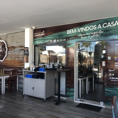 Fachada de café com porta de vidro e parede de madeira com texto de boas-vindas