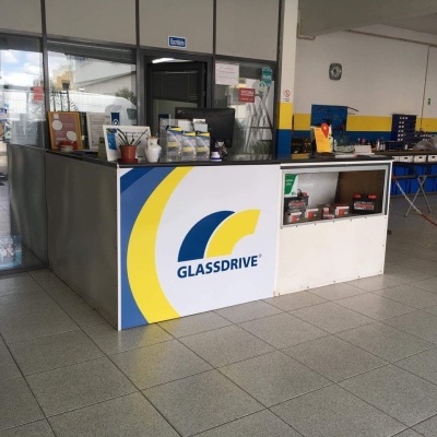 Balcão de atendimento Glassdrive com logótipo azul e amarelo em oficina
