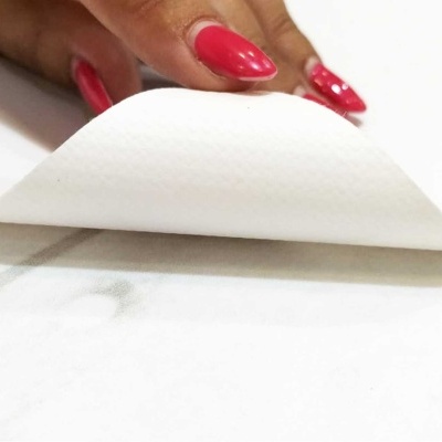 Mão com unhas vermelhas segurando uma folha branca fina dobrada