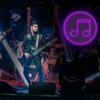 Banda de rock ao vivo com músicos a tocar guitarra e baixo, círculo luminoso rosa com nota musical ao fundo