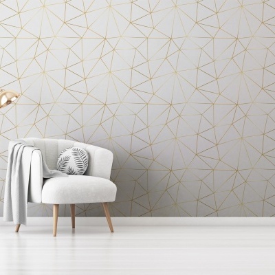 Cadeira cinzenta com almofada e candeeiro dourado junto a parede com padrão geométrico