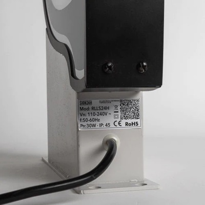 Dispositivo elétrico metálico com etiqueta técnica visível e cabo preto conectado.