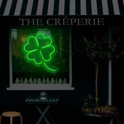 Fachada de creperia com néon verde trevo de quatro folhas