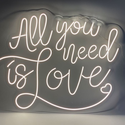 Neon branco com a frase 'All you need is love' numa parede cinzenta
