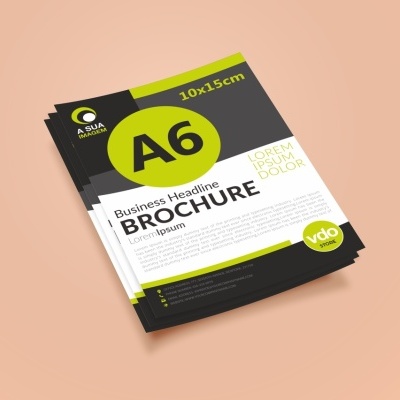 Folhetos de formato A6 em verde-limão e preto sobre superfície bege